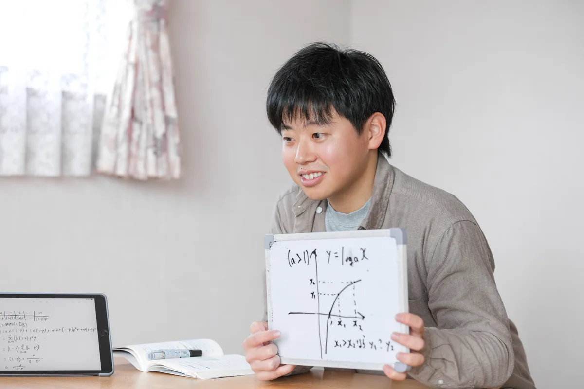 ホワイトボードに数学のグラフを描いて説明する平澤コーチ